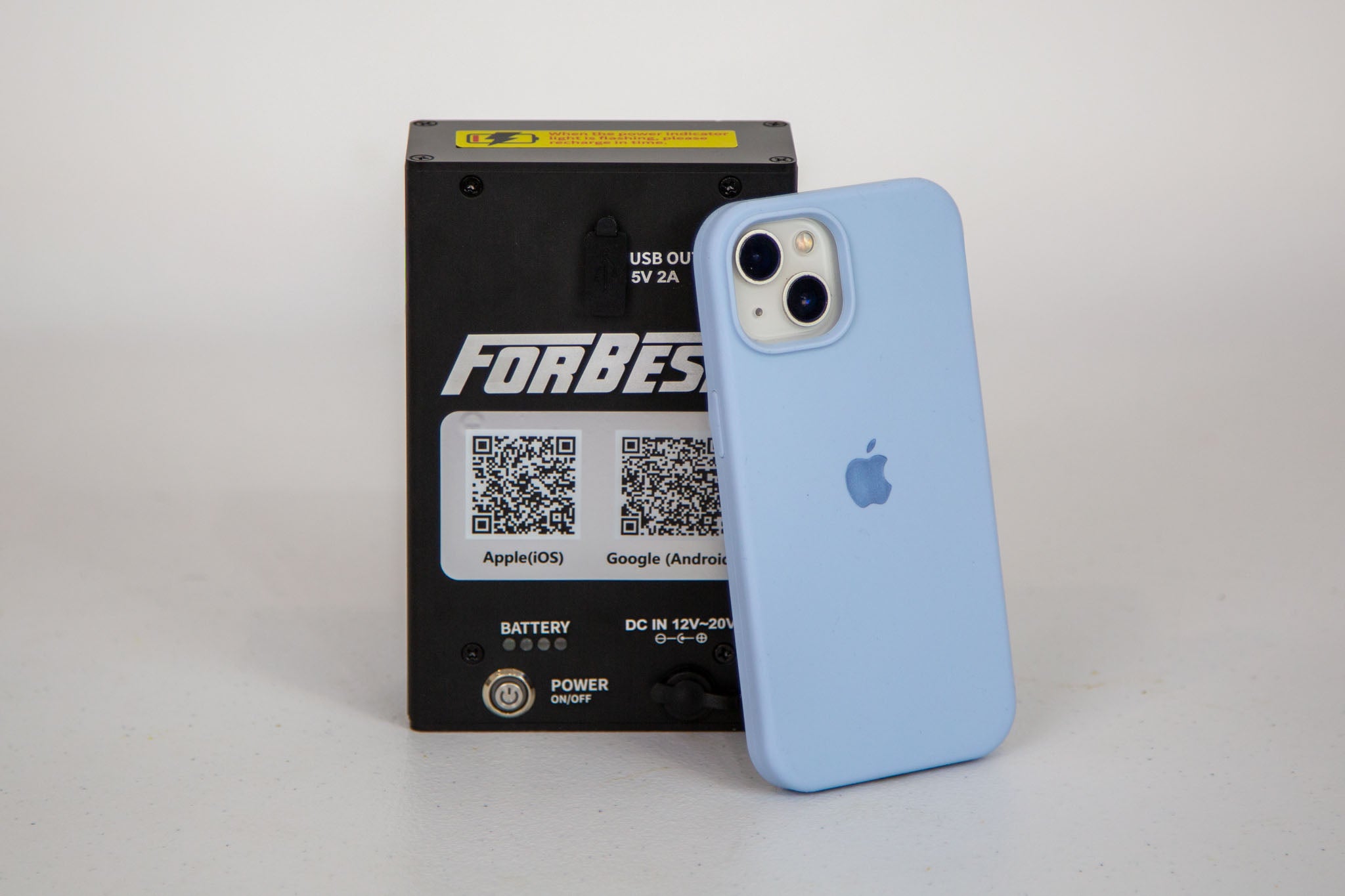 Blue phone case with Apple logo next to a black power bank with 'Forbes' branding